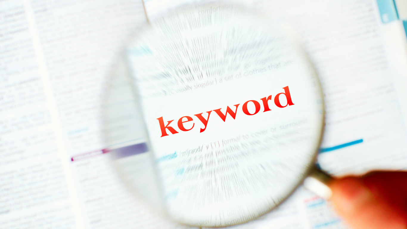 Magnifying glass highlighting the word “keyword” in red on a printed page, symbolizing the search for clarity in resolving keyword cannibalization issues.