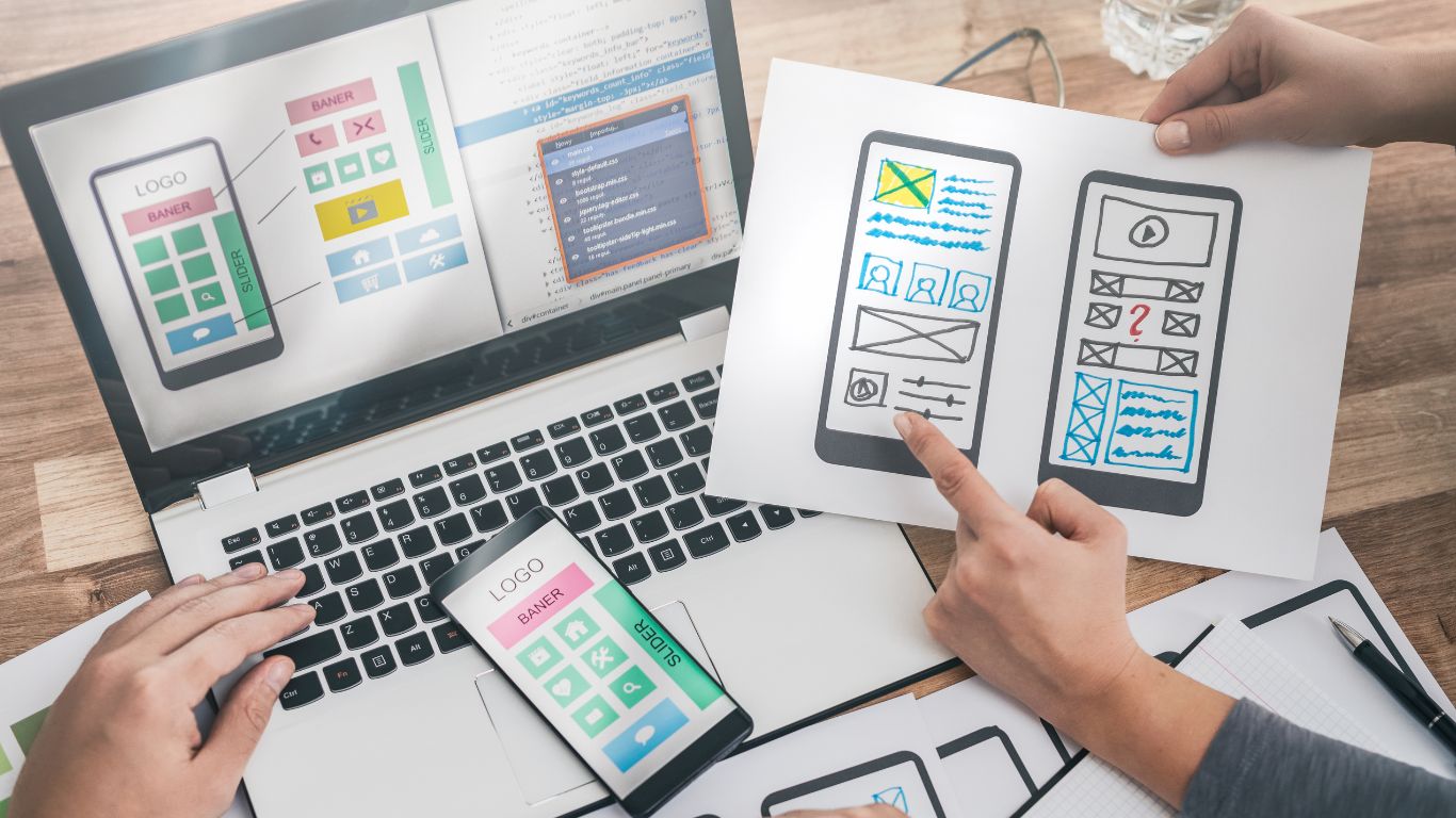 Website design mockup on a laptop and hand-drawn mobile app wireframes.